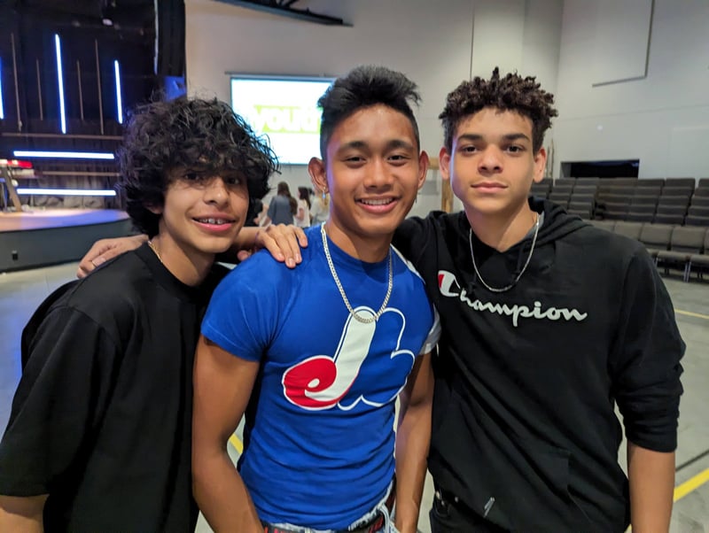 Three teen boys smiling and hugging