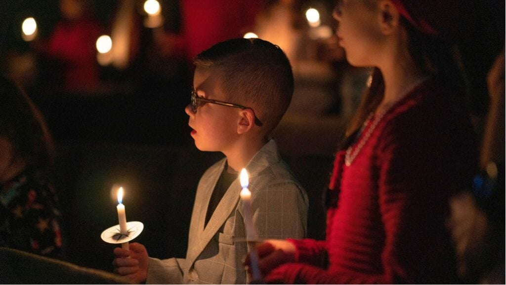 Little boy with glasses holding candle at Christmas Eve Service